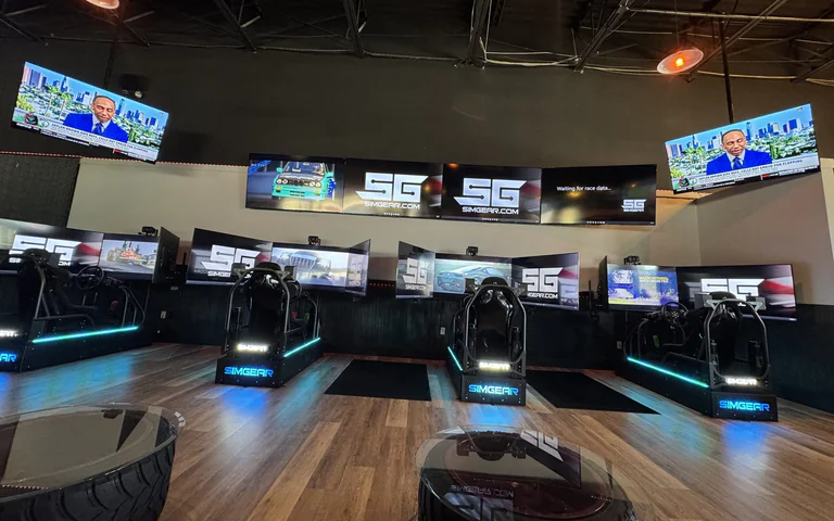 Racing simulator lounge row with seats, monitors and tire tables at On The Dunes Sports