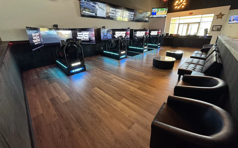 Wide view of racing simulator room with lounge seating at On The Dunes Sports