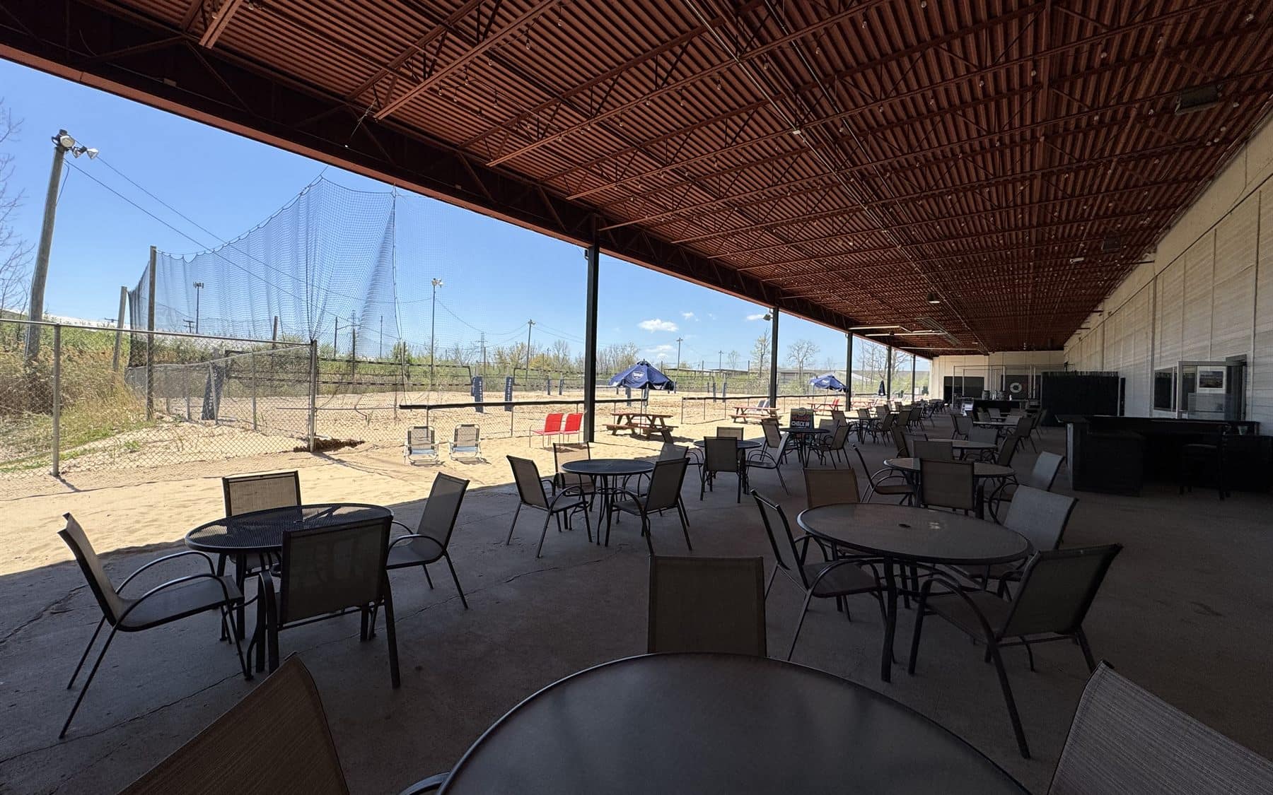 Wide covered patio seating area overlooking outdoor volleyball courts
